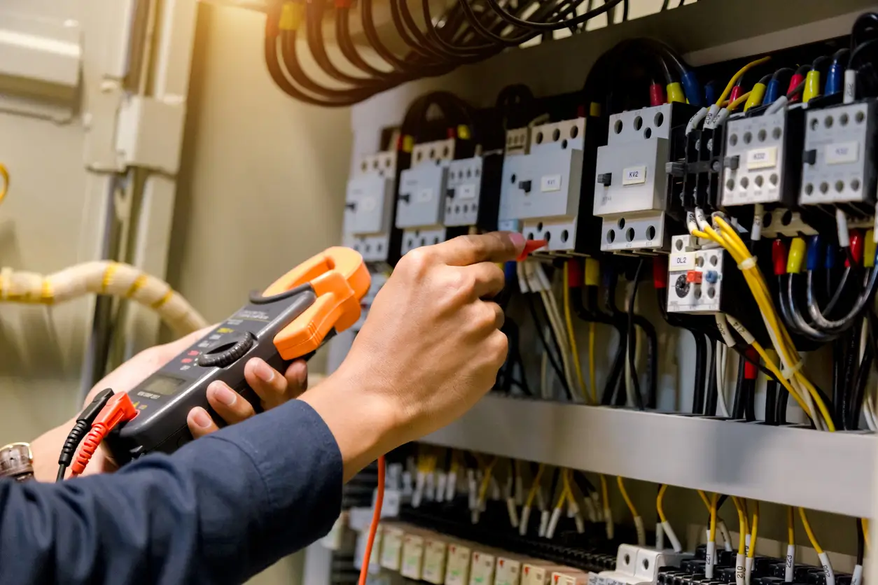 Elektrokontrollen von Navolta AG – Fachkraft überprüft elektrische Schaltanlage mit einem Messgerät