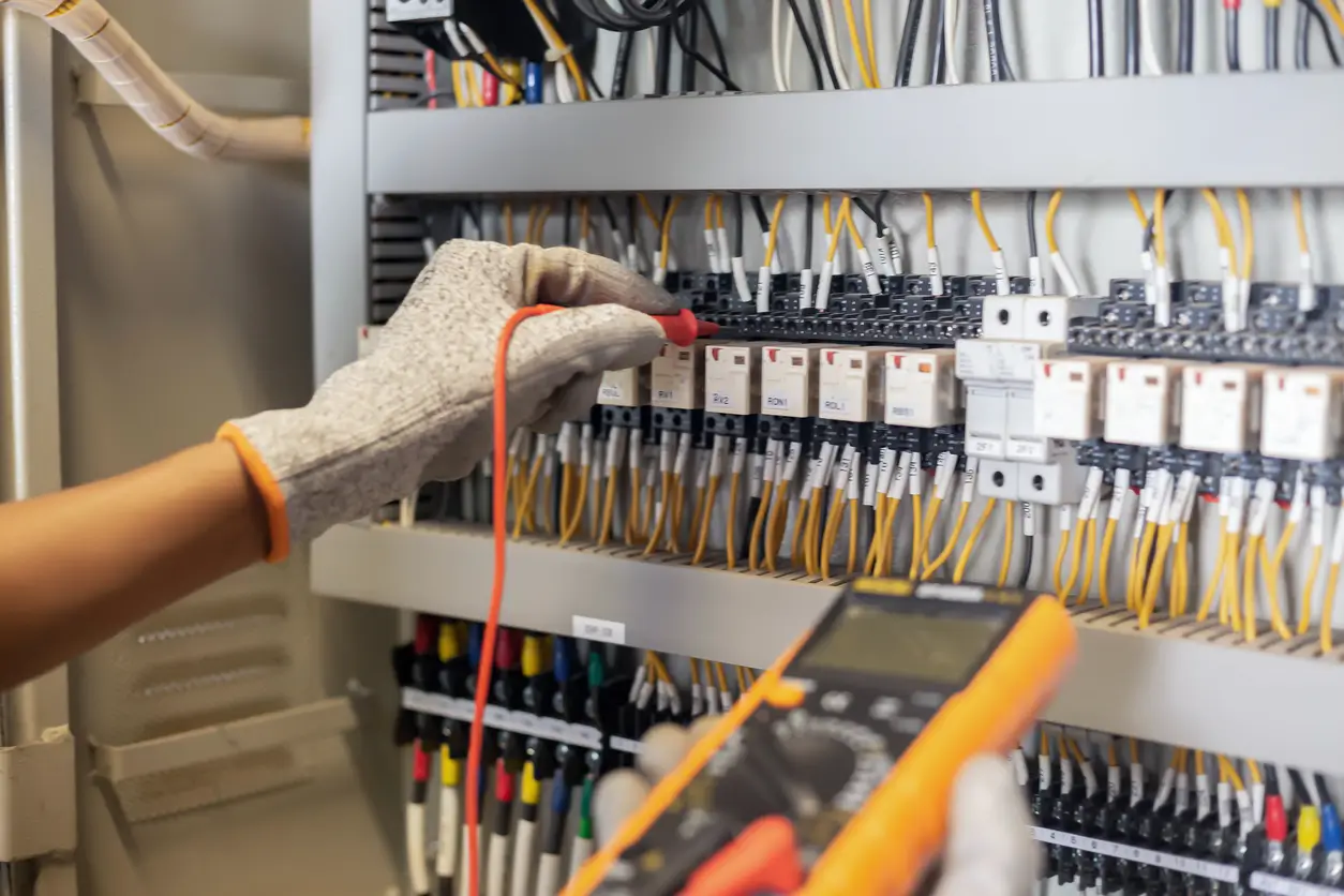Service & Unterhalt von Navolta AG – Fachkraft überprüft elektrische Schaltanlage mit einem Messgerät
